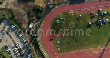 空中无人驾驶飞机在跑道体育场上空射击。 人们慢跑和挑战奥运会比赛和训练。